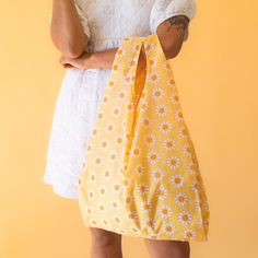 Say hello to your new must-have accessory for spring and summer - the Dreamy Daisy Reusable Bag! With its vibrant yellow, orange and ivory floral print, this nylon bag is not only perfect for grocery trips and beach days, but makes an adorable everyday accessory. Ditch single use plastic and strut your stuff in style with this versatile eye-catching Dreamy Daisy Reusable Bag. Everyday Yellow Floral Print Bags, Yellow Floral Print Bag For Daily Use, Yellow Floral Print Bags For Daily Use, Yellow Floral Print Everyday Bag, Lightweight White Beach Bag For Spring, Spring Reusable Rectangular Bags, Spring Rectangular Reusable Bag, Spring Rectangular Reusable Bags, Spring Reusable Bags