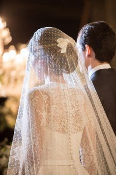 the bride and groom are looking at each other in front of chandelier lights