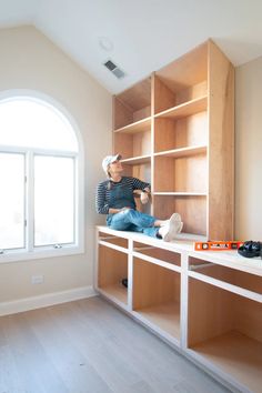 a man sitting on top of a wooden shelf