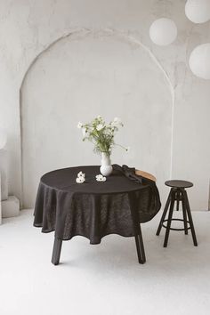 a black table with white flowers and two stools