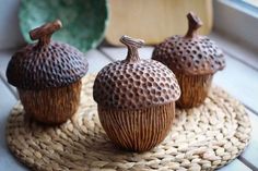 three brown ceramic figurines sitting on top of a woven place mat next to a window