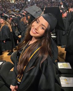 a woman in graduation gown and cap posing for a photo at the end of her graduation ceremony