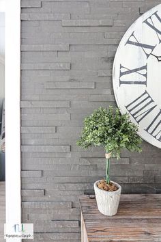 a clock mounted to the side of a brick wall next to a potted plant