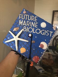 a blue graduation cap with the words future marine biologist written on it and seashells