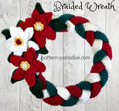 a crocheted wreath with flowers and leaves is shown on a white wooden background