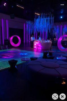 a room with purple lighting and round tables