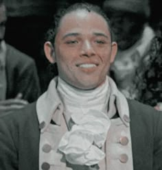 a man in a suit and tie is smiling at the camera while wearing a scarf around his neck