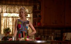 a woman standing in front of a table with plates and glasses on top of it