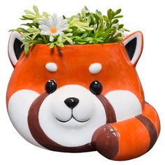 a ceramic red panda planter with daisies in it's mouth and eyes