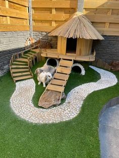 a dog house made out of pallet wood and artificial grass, with stairs leading up to the roof