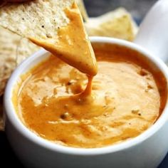 a tortilla chip being dipped into a bowl of dip