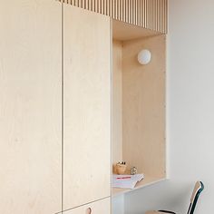 a chair sitting in front of a wooden cabinet next to a white wall and floor