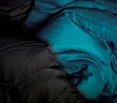 an unmade bed with black and blue sheets