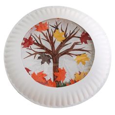 a paper plate with leaves on it and a tree painted on the inside of it