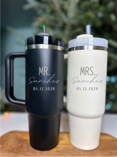 two personalized coffee mugs sitting on top of a wooden board