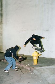 two people doing tricks on skateboards near a fire hydrant