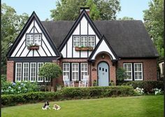 a house with two dogs sitting in the front yard and one dog laying on the lawn