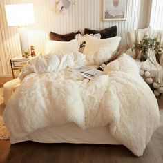 a bed with white fur on it in a bedroom next to two lamps and pictures