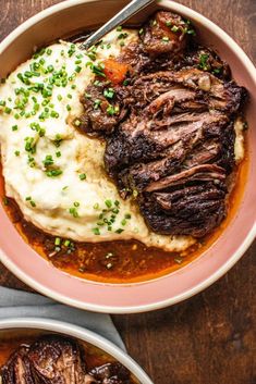 a bowl filled with meat and mashed potatoes on top of a wooden table next to a fork