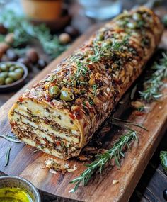 a large piece of food sitting on top of a wooden cutting board next to olives