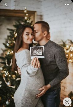 a pregnant woman is holding up a christmas card with the image of her husband on it