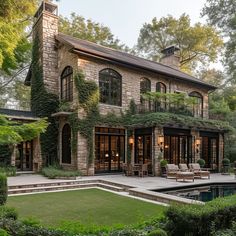 a large stone house with lots of greenery on the front and side walls, surrounded by lush green trees