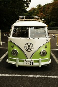 a green and white vw bus parked in a parking lot