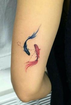 a woman with a tattoo on her arm that has two fish in it