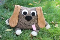 a crocheted dog sitting in the grass with its tongue out and eyes wide open