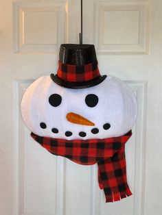 a snowman wearing a hat and scarf hanging from a door