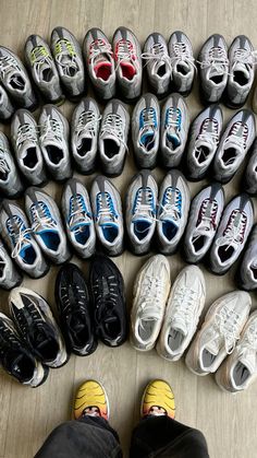 many pairs of shoes are lined up on the floor with one person's feet