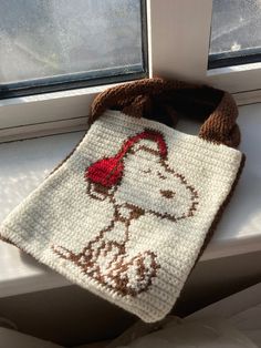 a crocheted dog bag sitting on top of a window sill next to a window