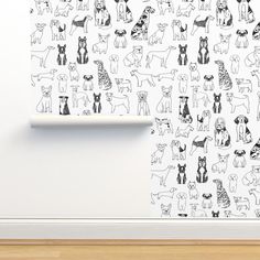 a white wall with black and white dogs drawn on it, next to a wooden floor