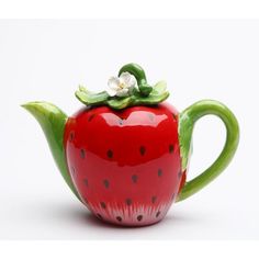 a red ceramic teapot with a white flower sitting on it's top,