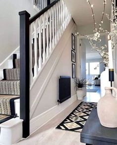 an entry way with stairs, vases and pictures on the wall next to it