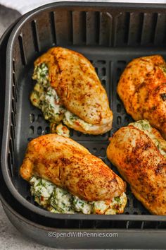 four pieces of chicken in a pan with spinach and cheese on the side, ready to be cooked