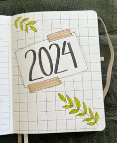 an open notebook with the number 2094 written on it and green leaves around it