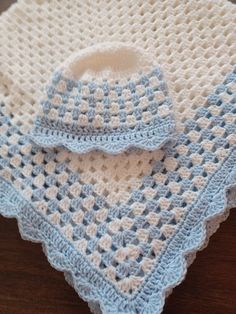 a blue and white crocheted blanket sitting on top of a wooden table next to a pot holder