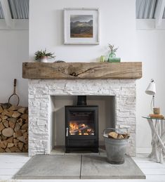 a fire place in a living room with logs on the floor and a painting above it