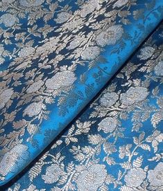 a blue and silver fabric with white flowers on the top, is laying down next to each other