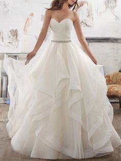 a woman in a strapless wedding dress with ruffles and beading on the skirt