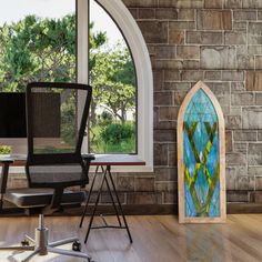 a chair and desk in front of a brick wall with a stained glass window on it