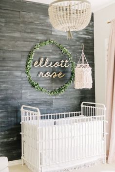 a white crib in front of a wooden wall with a sign that says elloti rose