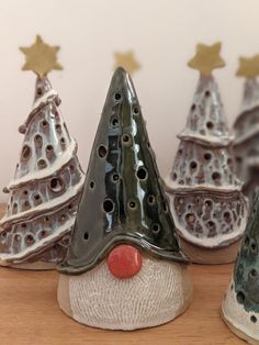 three ceramic christmas trees with gold stars on top and one has a red nose, while the other is green