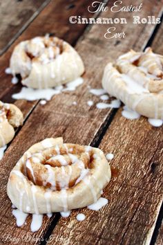 cinnamon rolls with icing sitting on top of a wooden table