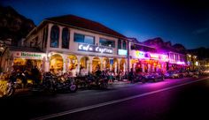 a group of motorcycles are parked in front of a building at night with neon lights