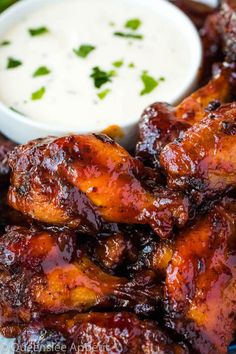 barbecue chicken wings with dipping sauce on the side and green garnish around them