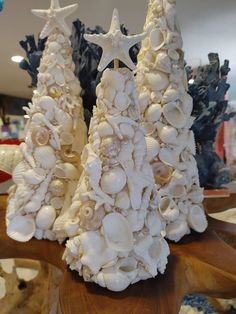 two white christmas trees made out of seashells and starfish on a table