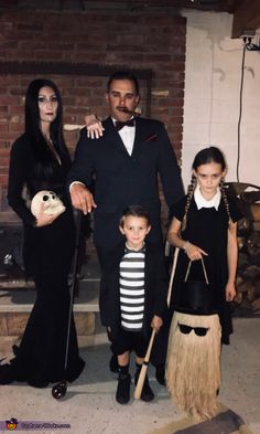 a family dressed up for halloween standing in front of a fire place with brooms