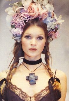 a woman with flowers in her hair wearing a choker and necklace on the catwalk